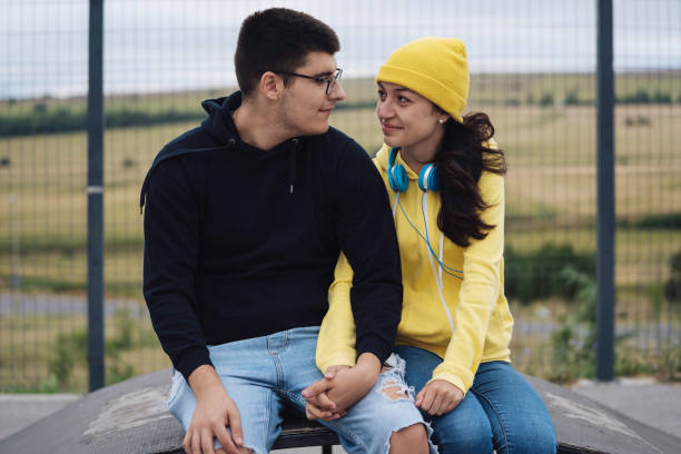 istock Young couple holding hands sitting close together smiling 2162970211