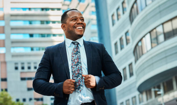 Confident black businessman smiling outdoors in cityscape. Professional urban lifestyle and success concept, business portrait.