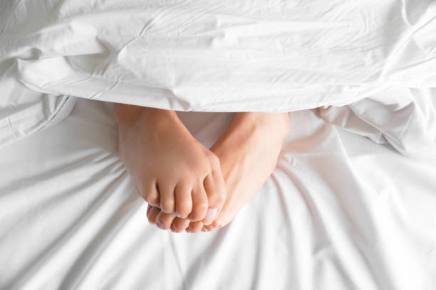 istock Couple feet under sheets on the bed at home. 2162978033