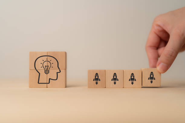 istock Idea launch strategy concept. Wooden blocks depicting a head with a lightbulb inside and rocket icons, symbolizing the concept of transforming ideas into action and launching new projects. 2162979604