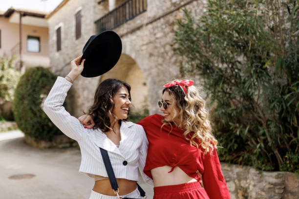 Beautiful young female friends having great time together while walking through old coastal town
