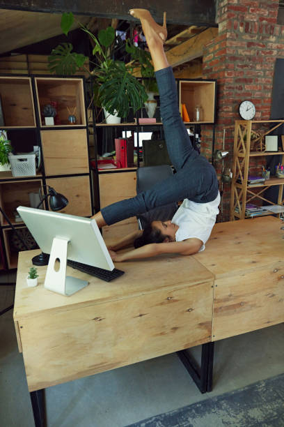 istock Woman, office worker doing flexible yoga exercises on her desk, surrounded by computer and supplies. Fitness at work 2162985532
