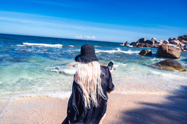 A Blonde Woman appraoches the sea on an empty beach in the UNESCO protected Nui Chua National Park, Vietnam
