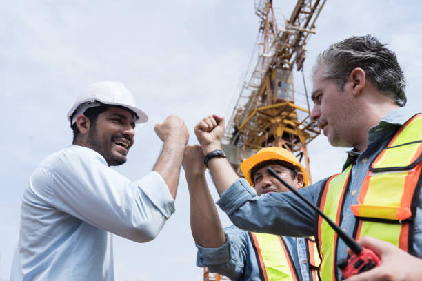 istock Team of male engineer construction standing and raise hands together at construction site. Group of male construction builder working at construction site. Unity and teamwork concept 2162997234