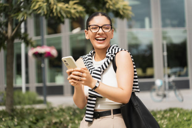 istock Stylish female student multitasking with her smartphone amidst an urban backdrop, reflecting the dynamic and connected life of today's youth. Ideal for education, technology 2162997387
