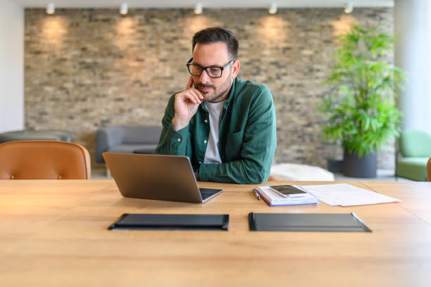 istock Portrait of confident web designer in glasses developing computer software at desk in modern office 2162997998