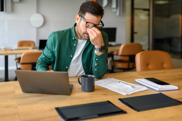 istock Exhausted male manager rubbing eyes in stress while working over project on laptop at his workplace 2162998062