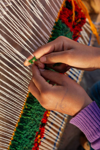 Berber girl weaving a carpet in a traditional house, Ouarzazate, Morocco. This old fashined form of weaving is very popular in the High Atlas mountains, specially in villages near Ouarzazate town.