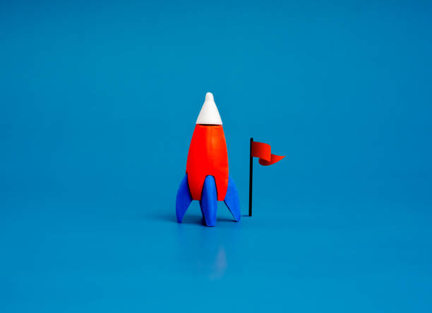 istock A small toy rocket was parked next to the red flag, isolated on blue background, minimal style. Creative innovation and ideas, inspiration, education and learnings, business startup growth concept. 2163000848