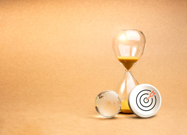 istock Environmental care sustainable goal, conserve resources, save planet concept. 3d Target icon badge and small glass world globe near hourglass isolated on eco brown background with copy space. 2163000872