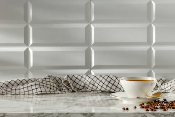 istock Stone marble kitchen countertop table with white tiled wall background with copy space for products. Checkered  kitchencloth and a cup of coffee and coffee beans. 2163001593