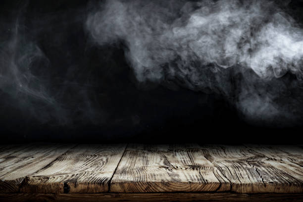 istock Wooden board table top with empty copy space and black wall with smoke background. 2163001940