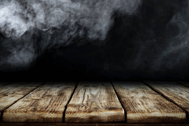istock Wooden board table top with empty copy space and black wall with smoke background. 2163001970