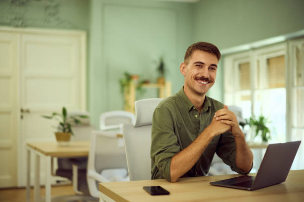 istock A smiling man with a mustache, posing for the camera while working in the co-working space. 2163003125