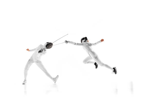 istock Two female fencers engage in training session, practicing their footwork and blade control in motion against white studio background. 2163005764