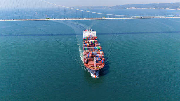 istock Aerial view of a cargo ship passing under bridge. Cargo Ship Beneath Bridge. 2163009083