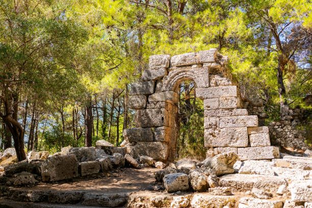 A stone archway with a small opening in the middle. The archway is surrounded by trees and rocks