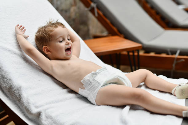 Little baby girl in diapers playing with toy blocks in bed