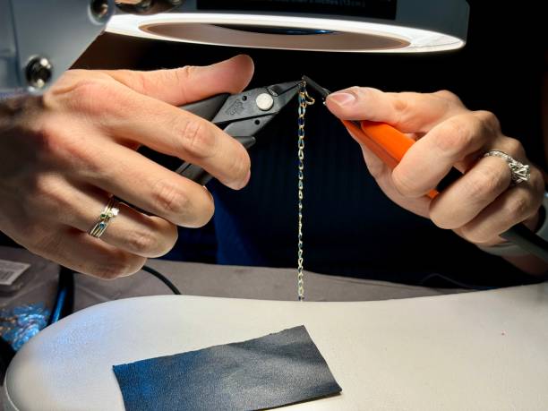 A permanent jewelry designer uses tools (including pliers) to make jewelry