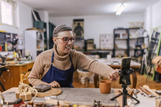 istock Jeweller reaching out to phone in creative workshop setup. 2163020793