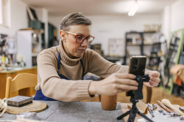 istock Jeweller adjusting phone on tripod in creative workshop. 2163022226