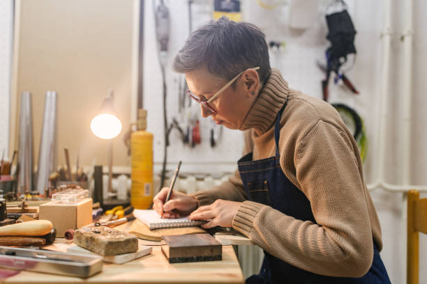 istock Individual engaged in making jewelry at cluttered bench. 2163022464