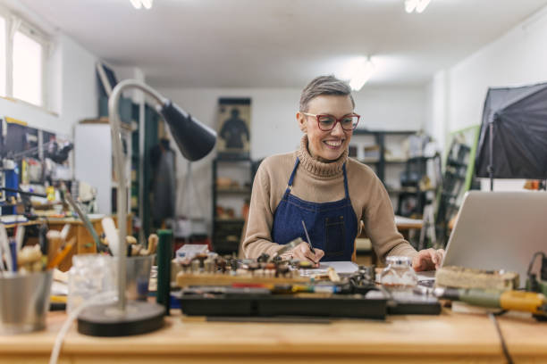 istock Focused jeweller in blue apron working in a studio. 2163022926