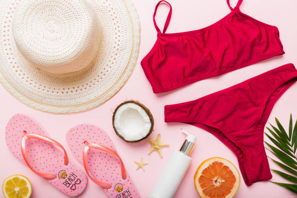 istock Swimming pool accessories concept. Top view of beach items on table, bright bikini, straw hat, and sunscreen skincare cream. Colorful beach wear. top view Flat lay, copy space 2163023574