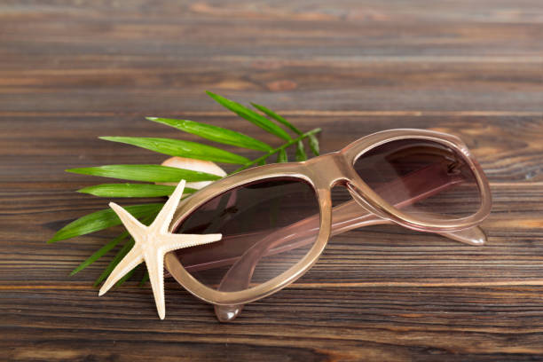 sunglasses with seashell lying on table background. Sunglasses on summer background. Top view flat lay with copy space for text.