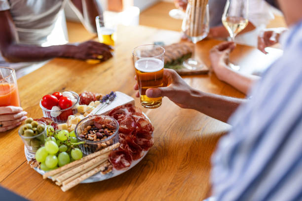Group of friends having a good time, enjoying drinks and snacks around a table. The scene is vibrant and filled with joy and laughter.