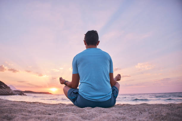 istock Man on the beach doing yoga at sunset 2163026253