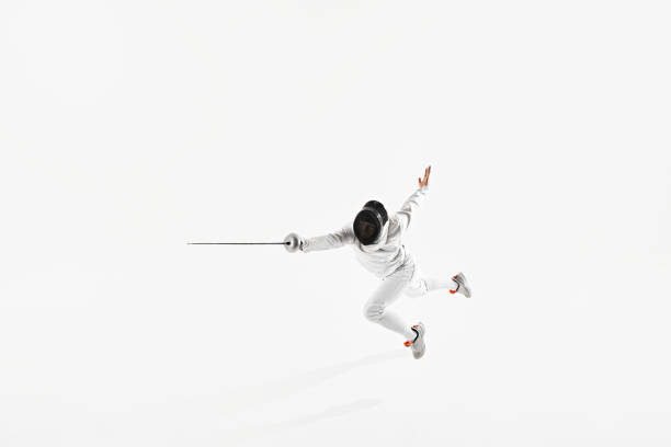 istock Fencer, outfitted in white suit and mask, strikes attacking pose with their rapier thrust forward against white studio background. 2163028730