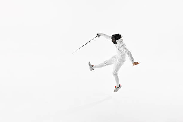 istock Fencer in complete white attire, including mask, depicted in mid-leap with their rapier extended against white studio background. 2163028735