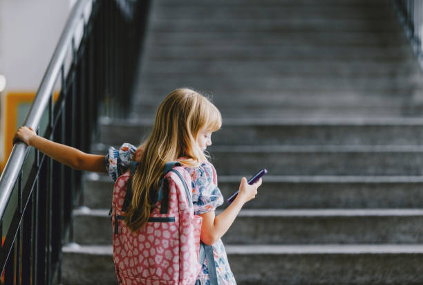 Young Girl Holding Phone with Backpack on School Staircase