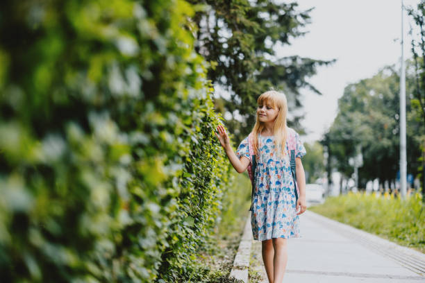 Cute little girl hugging  tree in the garden in a green grass backyard.