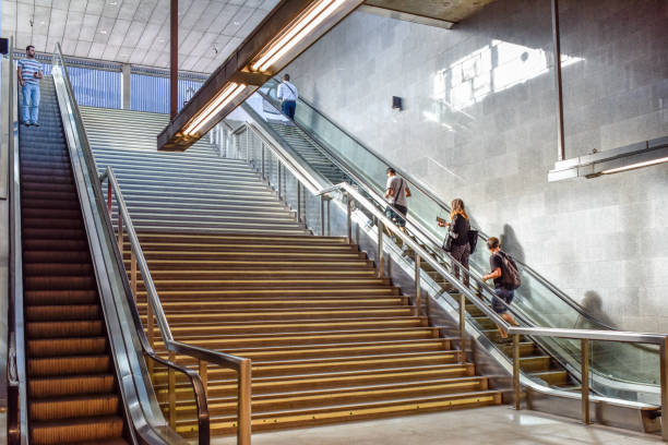 A view of the staircase and escalator at San Bernardo Metro Station in Seville, Andalusia, Spain. People are using the stairs and escalator.