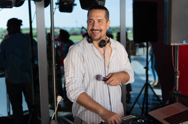 istock A Latino man is standing in front of a DJ booth with a microphone. 2163037193