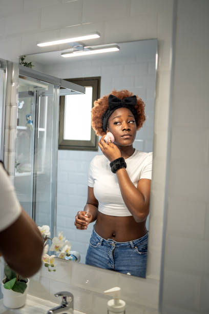istock Young woman using a reusable sponge pad to apply makeup in a modern bathroom for a flawless finish 2163039087