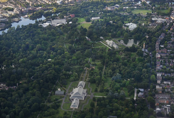 Arial Shot of Kew Royal Botanical gardens taken from the window of my passing air liner coming into land at Heathrow Airport. Kew is on the flight path into London airport\nAll the main greenhouses are visible in including The Temperate greenhouse (bottom of frame) and Palm House (off centre) also the river Thames top left. Kew Gardens are a famous West London attraction