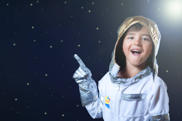 istock Kid in astronaut costume pointing far away in space copy, isolated on starry space background. 2163040899