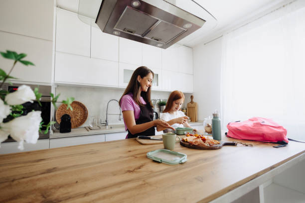 Mother with her daughter preparing breakfast at kitchen