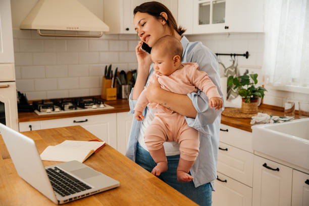 istock Young mother working on a computer from home together with her baby 2163050962