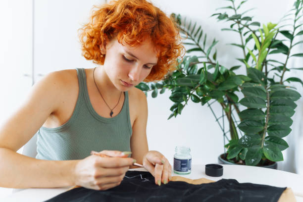 istock young woman draws picture on clothes with paints, handmade craft work. Customization 2163052299
