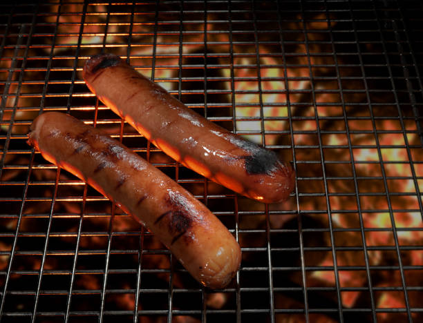 Delicious grilled sausages are sizzling on the BBQ grill, creating an irresistible smoky flavor in the air