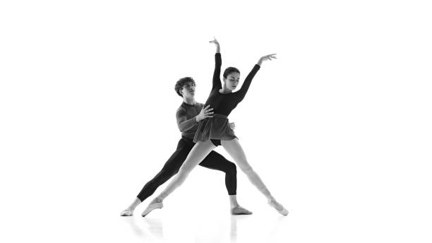 istock Ballet partners perfecting their form during practice session against white studio background. Black and white filter. 2163060440