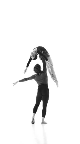istock Fluidity and strength. Man and woman, ballet pair practice together against white studio background. Black and white filter. 2163060452