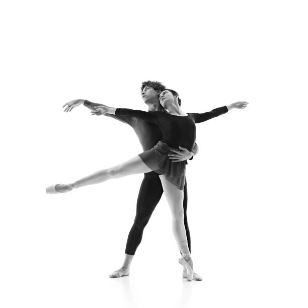 istock Grace and elegance. Young ballet dancers training in motion against white studio background. Monochrome filter. 2163060461