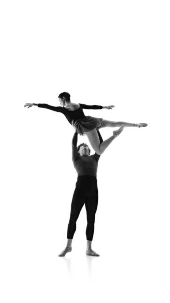 istock Ballet dancers in pair refining their technique in perfect harmony against white studio background. Monochrome filter. 2163060471