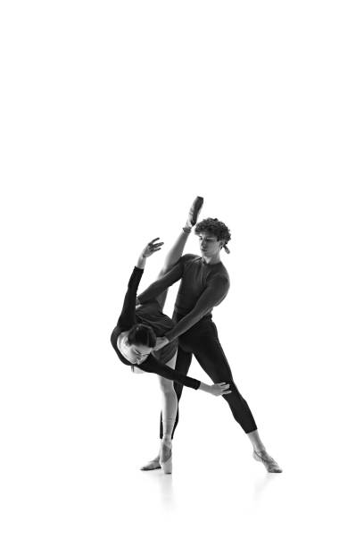 istock Ballet duo, graceful man and woman, perfecting dynamic bend against white studio background. Monochrome filter. 2163060473
