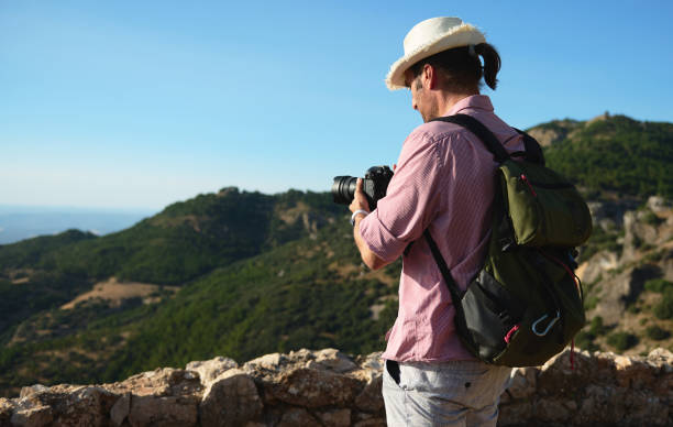 istock Man photographing mountainous landscape on a sunny day with backpack and hat 2163062191